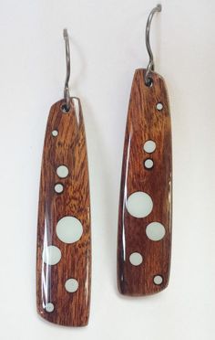 pair of wooden earrings with white dots on the outside and wood in the inside, hanging from hooks