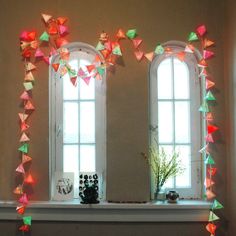 two windows are decorated with bright colored paper cranes on the mantle in front of them