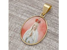 -Exclusive religious themed pendant mounted in 14k yellow gold, featuring a beautiful image of the Virgin Mary in prayer, on high definition porcelain. Large upper ring where you can insert a chain. -The Mother Mary on porcelain that characterizes this medal is unalterable over time, can be used by the sea, in the pool and in the shower. -Handcrafted product of Italian manufacture, regularly marked with the title of the 14k gold (585) and the manufacturer. -CHARACTERISTICS 14k (585) yellow gold Virgin Mary Pendant, The Virgin Mary, Saint Mary, Italian Jewelry, In The Pool, Mother Mary, Pendant Gold, By The Sea, Virgin Mary