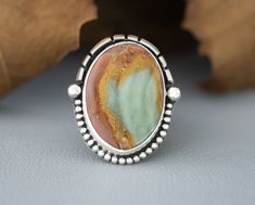 Handcrafted Sterling Silver Statement Ring with Polychrome Jasper. This chunky ring has been handmade using 925 Sterling Silver that has been fused, stamped and oxidized. The setting is an oval Polychrome Jasper Cabochon that is in a Bezel setting accented with cut out triangle wire and beads. The setting is 37mm x 31mm and the tapered thick wide band band is 3/4" then narrows to 1/8" for a comfortable fit. This ring cannot be resized. Size 7 1/2 Introducing our new Polychrome Jasper Silver Statement Cocktail Ring! This unique, coastal cowgirl piece is a true work of art, showcasing the natural beauty of Polychrome Jasper. The vibrant colors and intricate patterns of this stone are beautifully complemented by the captivating silver setting. From the bold, chunky design to the exquisite cra Handmade Silver Jasper Rings, Handmade Jasper Rings For Gift, Handmade Jasper Rings As Gift, Handmade Jasper Rings As A Gift, Unique Jasper Rings For Gift, Rustic Sterling Silver Turquoise Ring Gift, Untreated Sterling Silver Rings With Rustic Style, Jasper Gemstone Rings For Gifts, Jasper Gemstone Rings As A Gift