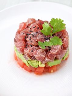 a white plate topped with an avocado and tomato salad covered in black pepper