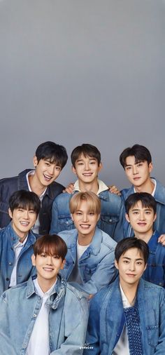 a group of young men standing next to each other in front of a gray background