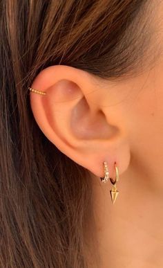 a close up of a person's ear wearing gold earrings with small diamonds on them