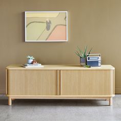 a sideboard with a painting on the wall above it and a radio in front of it