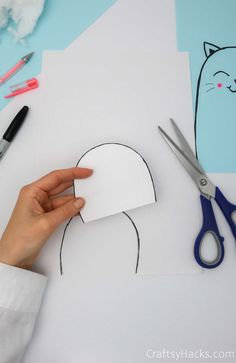 someone cutting out a paper cat head with scissors