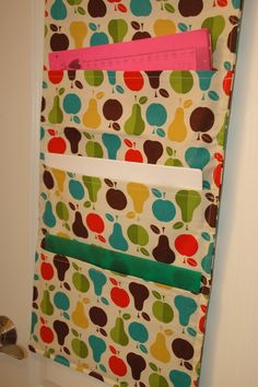 a toilet paper roll holder with apples and pears on it, hanging from the wall