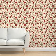 a white couch sitting in front of a wall with red flowers on it's side