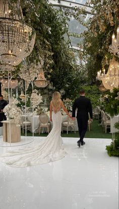 a bride and groom walking down the aisle at their wedding reception in an elegant garden setting