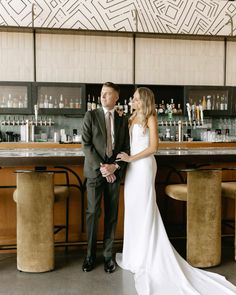 a man and woman standing in front of a bar