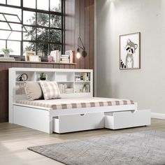 a white bed with drawers underneath it in a room