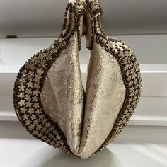 Subtle Paisley Fabric Fortune Cookie Purse. Golden Beaded Bag Gold Metallic. Zip Top, Folds In Like A Fortune Cookie Shape. Two Beaded Round Handles. Gold Star Bead Accents. Comes In Original Cloth Envelope. Excellent Condition, No Flaws Found. Clean Interior. Approximate Flat Lay Measurements: When Closed: 7” Wide, 8.5” Long When Open: 10” Wide, 6” Tall Comes From A Smoke And Pet-Free Home. Beige Pouch Potli Bag For Evening, Cream Handheld Clutch For Party, Elegant Potli Bag With Pearl Handle, Traditional Evening Clutch With Pearl Handle, Festive Clutch With Pearl Handle, Beige Clutch Pouch For Parties, Elegant Festive Pouch Potli Bag, Evening Potli Bag With Gold Embroidery, Elegant Evening Bag With Pearl Handle For Festive Occasions