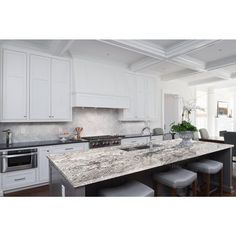 a kitchen with white cabinets and marble counter tops, along with stools that match the hardwood flooring