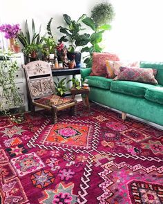 a living room with green couches and colorful rugs on the floor next to potted plants