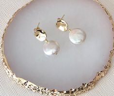 Gold Pearl Earrings are a hammered gold stud with gorgeous freshwater pearl coin bead drop. The earring measures approximately 2.8cm from top of gold stud section. The earring fixing  is made from gold plated hammered gold.  These Gold Pearl Earrings would make a wonderful gift for your bridesmaids too! And they are not just for weddings either - why not wear them on a night out.? They also make a fabulous gift! They are beautifully packaged in a pretty white or grey velvet pouch. NOTE: THIS ITEM TAKES APPROXIMATELY 1 WEEK TO COMPLETE - IF YOU REQUIRE IT SOONER, PLEASE CONTACT US BEFORE PLACING YOUR ORDER. Hammered Pearl Jewelry For Wedding, Hammered Drop Earrings For Wedding, Hammered Gold-plated Earrings For Wedding, Hammered Gold Plated Earrings For Wedding, Hammered Gold Plated Wedding Earrings, Hammered Round Wedding Earrings, Elegant Hammered Pearl Earrings For Wedding, Elegant Hammered Earrings For Wedding, Hammered Drop Pearl Earrings As Gift