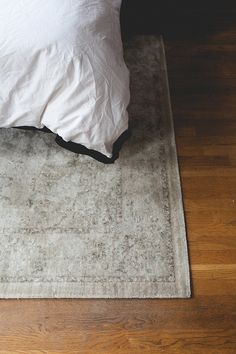 a bed sitting on top of a wooden floor next to a white pillow