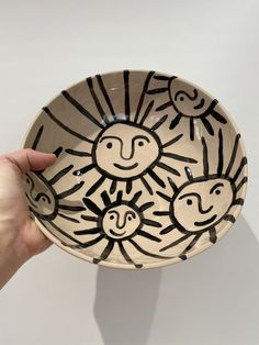 a hand holding a bowl with drawings on it