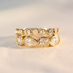 a gold ring with five pear shaped diamonds on it's side, sitting on a white surface