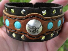 Vintage sterling silver Eagle   button concho  soldered screw back and  placed on bracelet. Turquoise color  gemstones tied with deer sinew.  Rust free  rivets and buckle closure. Thank you for your interesting  handcrafted THICK  dark brown, tobacco and back color genuine American  Buffalo Bison leather wristband.  It is  adjustable for small or medium or  large or X large XXL  wrist size Bracelet is  1.5  inch  wide. I can make customize to wrist size snaps closure if you prefer. Made in USA Totally with LOVE  Total  handmade , hand cut .   Please check my other items I make customize to wrist size bracelets and other jewelries. Nice gift for valentine's day,  Birthdays gift, Anniversary gift,  Graduation gift, Thanksgiving gift , Mother days gift, Father days gift. Thank you for interes Artisan Bracelet With Concho As Gift, Western Style Leather Bracelet With Concho, Western Style Leather Bracelet With Concho As Gift, Artisan Concho Bracelets For Gift, Artisan Concho Bracelet For Gift, Unique Concho Bracelets For Gift, Western Style Leather Bracelet Gift, Western Style Leather Bracelets For Gift, Unique Concho Bracelets As Gift