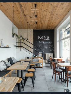 the interior of a restaurant with wooden tables and chairs, chalkboard on the wall