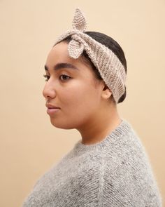 a woman wearing a knitted headband with a bow on it's side