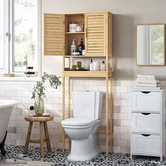 a white toilet sitting in a bathroom next to a bath tub and wooden cabinet above it