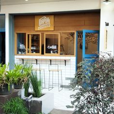 an outside view of a restaurant with plants in the foreground and signs on the wall