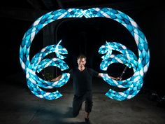 a man standing in front of a large blue and white snake shaped light up ring