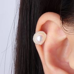 a close up of a person's ear with a pearl in the middle and a shell on top