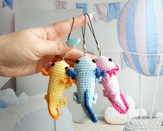 three tiny crocheted seahorses are hanging from a string in front of a hot air balloon