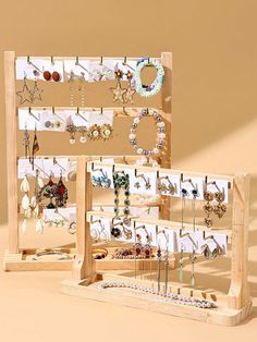 two wooden racks holding earrings and necklaces on display against a beige background with shadows from the wall