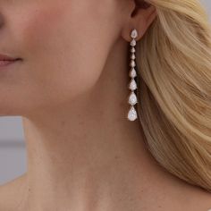 a woman with blonde hair wearing large diamond drop earrings on her ear and looking off to the side