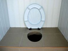 a white toilet sitting on top of a wooden floor next to a brown box with a black hole in it