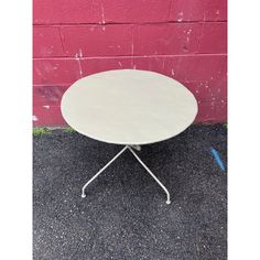 a white table sitting in front of a pink brick wall on the side of a road