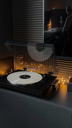 a record player is sitting on top of a table with some lights around it in the dark