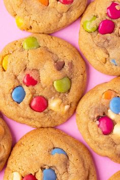 several cookies with m & m's and candy on top are arranged in a row