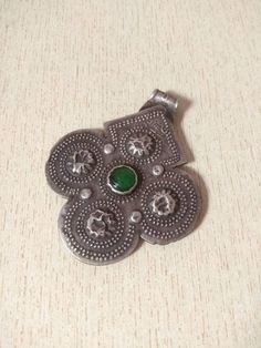 This is a beautiful silver berber pendant Foulet Khamsa finely chiselled four-lobed, with one green glass. This pendant is in good condition with Hallmarks. Length : 8 cm (3,1 inches) Width : 6,7 cm (2,6 inches) Weight : 29,4 g Green Amulet Pendant Jewelry, Green Medallion Amulet Jewelry, Traditional Green Jewelry With Large Pendant, Green Amulet-style Jewelry With Large Pendant, Green Engraved Amulet Jewelry, Green Oxidized Artisan Jewelry, Green Artisan Jewelry With Oxidized Finish, Artisan Green Jewelry With Oxidized Finish, Traditional Green Medallion Jewelry