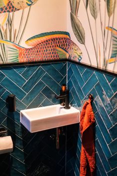 a bathroom with blue tiles and fish painted on the wall next to a white sink