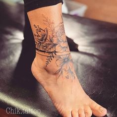 a woman's foot with flowers on it and a tattoo design on the ankle