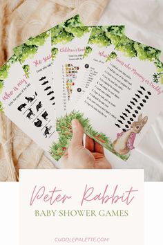 a person holding up four baby shower games with the words peter rabbit in pink and green