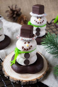 chocolate covered snowmen sitting on top of a piece of wood