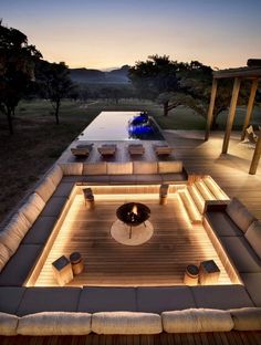 an outdoor living area with couches, tables and lights on the side of it