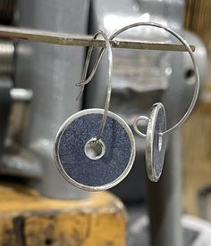 This is a lovely and unique pair of sterling silver earrings. They have inlay made from crushed blue azurite stones with a bit of sterling silver filings mixed in. The ear wire is semi-circular and feeds through the center of each earring. The settings each measure 18 mm in diameter and the total drop length is about 30 mm. Artisan Blue Hoop Earrings Nickel Free, Blue Sterling Silver Small Hoop Jewelry, Blue Sterling Silver Hoop Earrings Nickel-free, Blue Sterling Silver Hoop Earrings Nickel Free, Blue Sterling Silver Small Hoop Earrings, Small Blue Sterling Silver Hoop Earrings, Silver Lapis Lazuli Round Earrings, Silver Round Lapis Lazuli Earrings, Blue Sterling Silver Earrings With Polished Finish