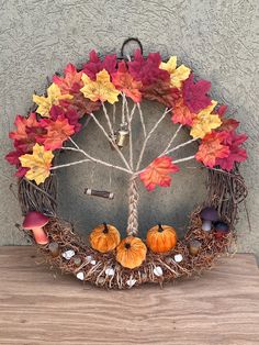 a fall wreath with leaves and acorns hanging on a wall next to a wooden table