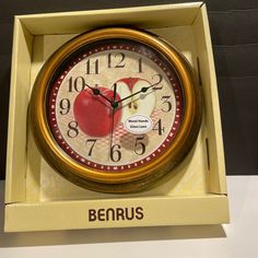 a clock with an apple on the face in a yellow box that says benrus