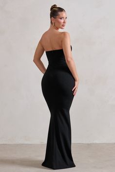 a woman in a black dress standing with her back to the camera