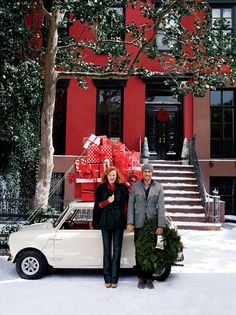 two people standing in front of a car with presents on it