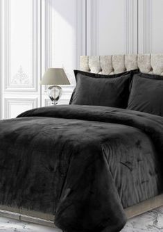 a black comforter set on a bed in a room with white walls and marble flooring