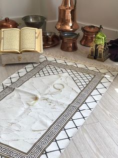 an open book sitting on top of a white rug next to other books and vases