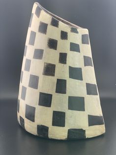 a black and white vase sitting on top of a table next to a gray wall