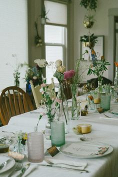 the table is set with plates and vases filled with flowers, candles and napkins